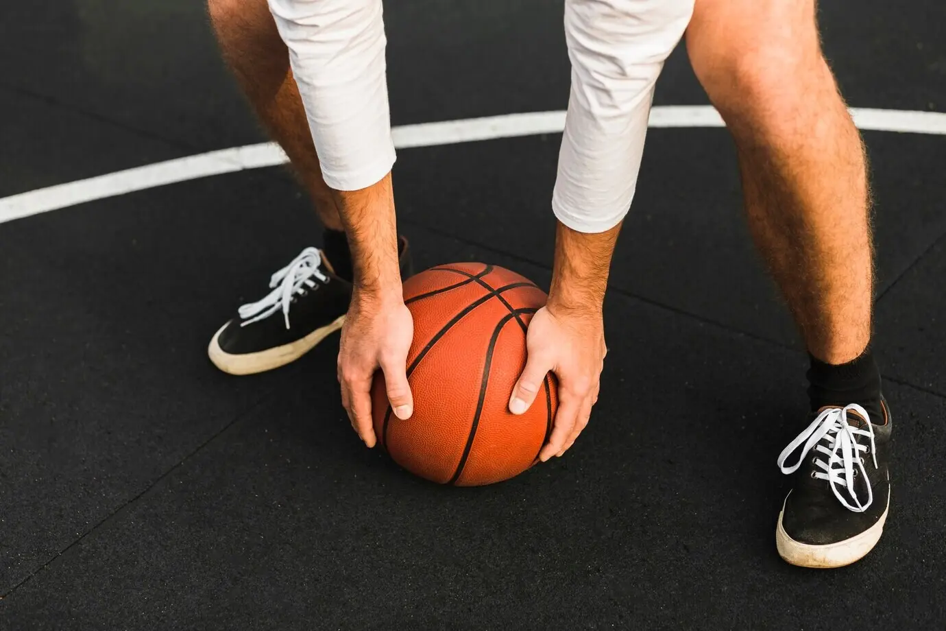 Неузнаваемый игрок держит баскетбольный мяч.